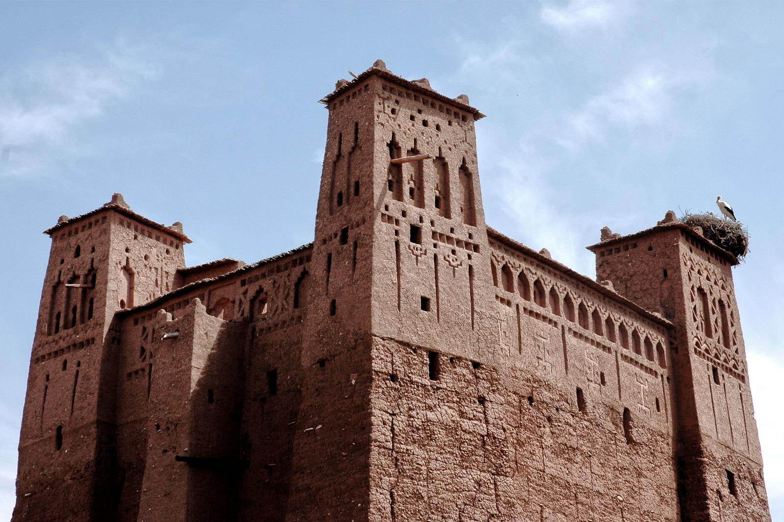 Tall earth kasbah towers under a blue sky in southern Morocco