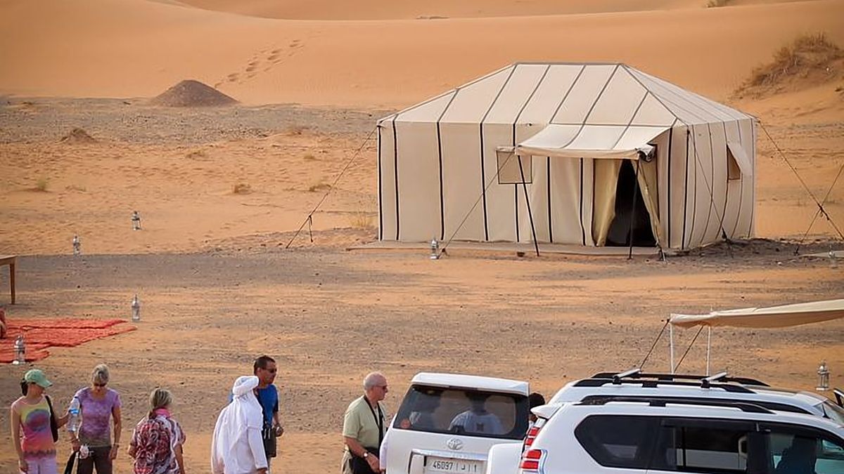 Desert camp and 4x4 vehicles among the sand dunes of Merzouga in the Sahara